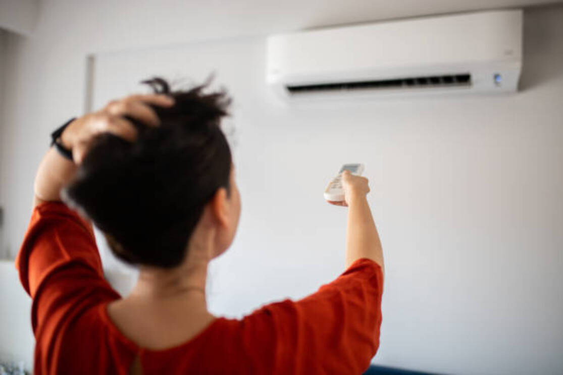Woman switching on air conditioner