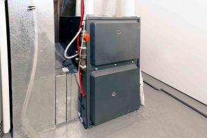 High-efficiency gas furnace installed in a home utility area, showing the metal cabinet, ductwork, and connected gas and electrical lines.