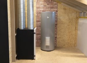 Modern water heater and HVAC ventilation unit installed in a utility room with wood paneling and brick accent wall.