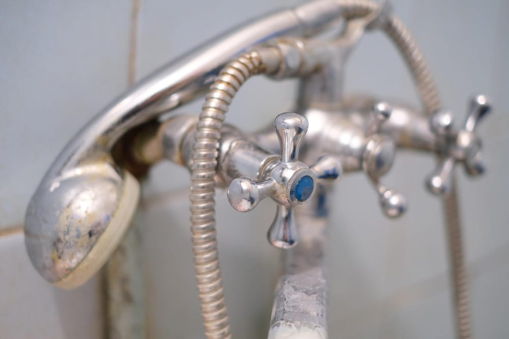 A bathroom water fixture covered in hard water residue