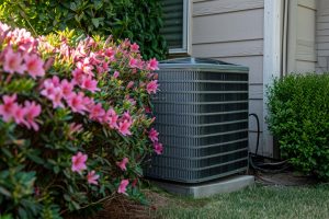 A modern HVAC unit in the lush, green backyard of a home