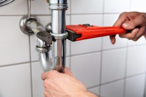 A wrench on a pipe being held by a hand, demonstrating Phoenix Plumbing prep for Monsoon Season.